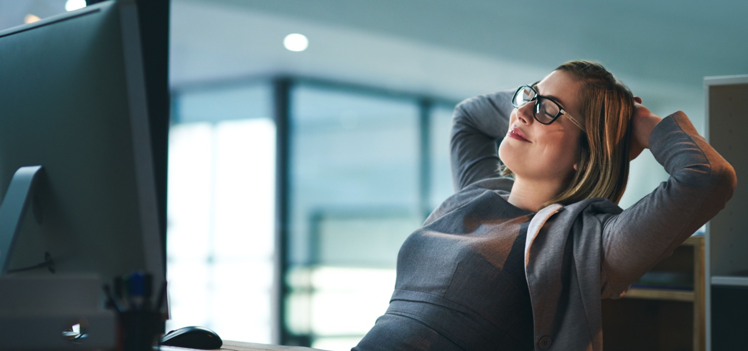 business woman reclining at her desk because she can manage multiple compliance standards easily